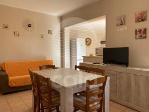 a living room with a dining room table and a tv at Villa Camelia in Torre Lapillo