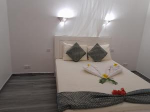 łóżko z dwoma poduszkami i kwiatami w obiekcie Villa santa avec piscine et jardin w mieście Pointe-aux-Piments