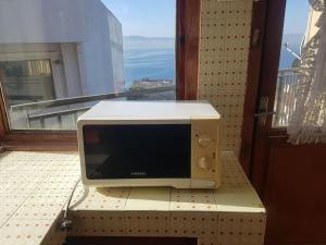 un four micro-ondes assis sur une boîte devant une fenêtre dans l'établissement Просторная квартира 2 plus 1 с панорамным видом на море, à Darıca