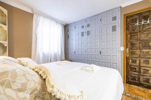 een slaapkamer met een wit bed en een deur bij Bonito y acogedor apartamento con terraza in Los Realejos