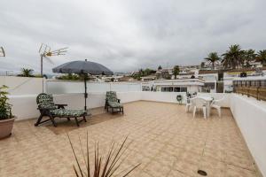 Bonito y acogedor apartamento con terraza في لوس رياليخوس: فناء به كراسي ومظلة على شرفة