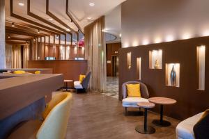 eine Lobby mit Stühlen und eine Bar mit gelben Kissen in der Unterkunft Dorint Airport-Hotel Zürich in Glattbrugg
