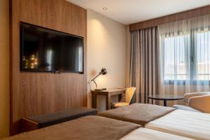 a hotel room with two beds and a flat screen tv at Hotel Granada Center in Granada