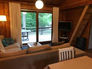 Chalet op rustig vakantiepark في Heure: غرفة معيشة مع أريكة ونافذة كبيرة