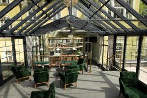 a conservatory with green chairs and a table at Villatoro in Zgorzelec