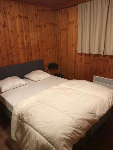 Chalet op rustig vakantiepark في Heure: سرير أبيض كبير في غرفة مع نافذة
