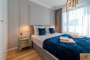 a bedroom with a large bed with blue sheets at Apartament Rosa De Lux in Mińsk Mazowiecki