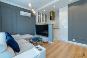 ein Wohnzimmer mit einem weißen Sofa und einem TV in der Unterkunft Apartament Rosa De Lux in Mińsk Mazowiecki