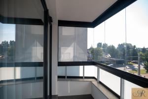 a balcony with glass windows and a view of a city at Apartament Rosa De Lux in Mińsk Mazowiecki