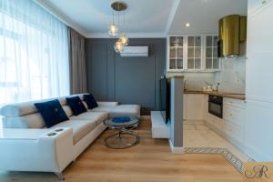 a living room with a white couch and a kitchen at Apartament Rosa De Lux in Mińsk Mazowiecki