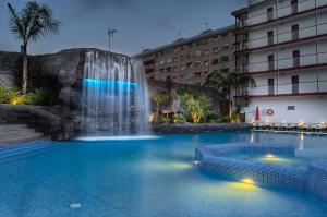 uma piscina com cascata em frente a um edifício em Hotel Papi em Malgrat de Mar