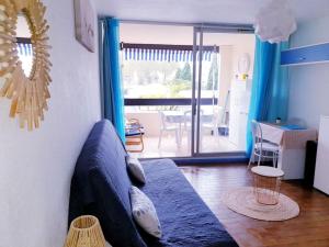 ein Wohnzimmer mit einem blauen Sofa und einem Tisch in der Unterkunft Agréable Studio Cabine - piscine - parking - proche Plage RICHELIEU in Cap d'Agde