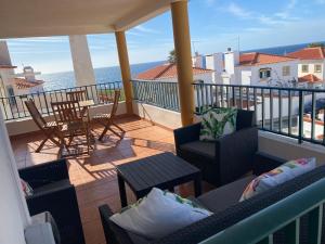 uma varanda com cadeiras e uma mesa e o oceano em Villa Kethellen em Porto Covo