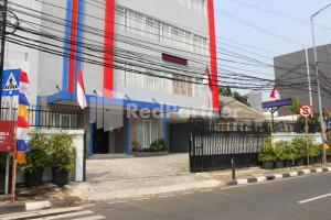 a building with flags in front of a street at Brahma Hotel Mitra RedDoorz in Jakarta