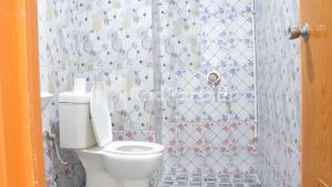 un bagno con wc e doccia piastrellata di Brahma Hotel Mitra RedDoorz a Giacarta