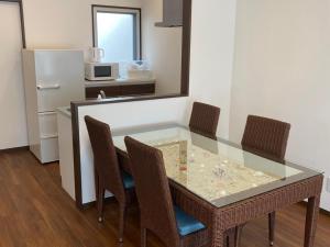 a kitchen with a glass table with chairs and a refrigerator at VILLA COZYSTAY92 宮古島 in Miyako Island