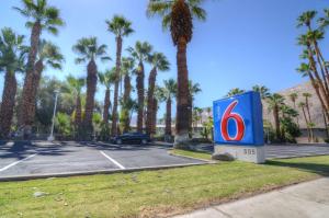 a sign in a parking lot with palm trees at Motel 6-Palm Springs, CA - East - Palm Canyon in Palm Springs