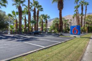 une voiture garée sur un parking avec des palmiers dans l'établissement Motel 6-Palm Springs, CA - East - Palm Canyon, à Palm Springs