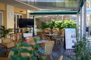 eine Restaurantterrasse mit Tischen und Stühlen und einem Flachbild-TV in der Unterkunft Coral beach house & food in Playa de Palma