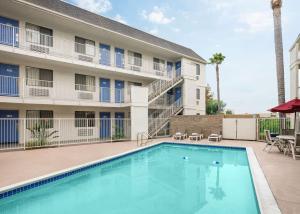 a swimming pool in front of a building with a hotel at Motel 6-Buena Park, CA - Knotts Berry Farm - Disneyland in Buena Park