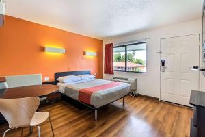 a bedroom with a bed and a table and a room with orange walls at Motel 6-Sunnyvale, CA - South in Sunnyvale