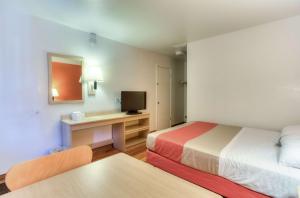 a room with two beds and a desk with a television at Motel 6-Tigard, OR - Portland South - Lake Oswego in Tigard