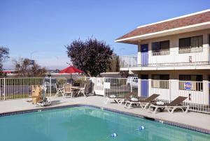 a pool in front of a hotel with chairs and a patio at Motel 6-Troutdale, OR - Portland East in Troutdale