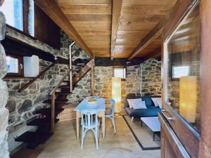 Habitación con mesa, sillas y pared de piedra. en Apartamentos Rurales El Lleron en Caso