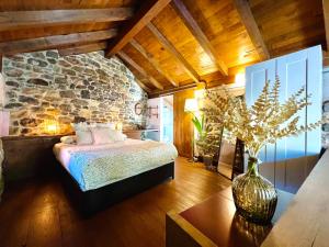 1 dormitorio con cama y pared de piedra en Apartamentos Rurales El Lleron, en Caso