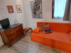 uma sala de estar com um sofá laranja e uma televisão em ISEPO APARTMENT em Veneza