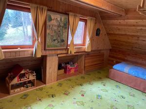 um quarto de um chalé de madeira com uma cama e janelas em Horská chalupa Pluskovjanka em Velké Karlovice
