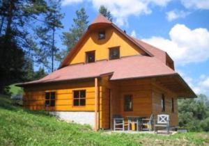 uma casa com um telhado de gambrel no topo de uma colina em Horská chalupa Pluskovjanka em Velké Karlovice