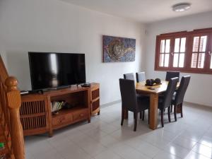 a dining room with a table and a flat screen tv at Villa Roferos 32 in Puerto del Carmen