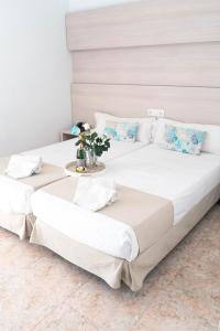 two beds with white sheets and a tray of flowers at Coral beach house & food in Playa de Palma