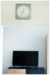 eine Uhr, die an einer Wand über einem Fernseher hängt in der Unterkunft Color24 Centrum Nisko in Nisko