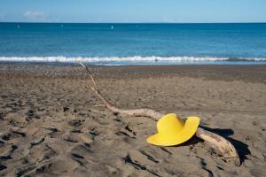 un cappello giallo da cowboy seduto sulla spiaggia di Camping Il Capannino Glamping Village a Marina di Bibbona