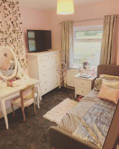 a bedroom with a bed and a desk and a television at Catchdale Moss Cottage 