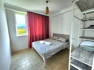 1 dormitorio con cama y cortina roja en beachfront apartments ,,kapro-one,,, en Ureki