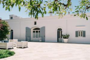 un edificio bianco con due sedie bianche in un cortile di Masseria Don Luigi-Luxury Farmhouse a Savelletri