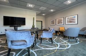 a waiting room with chairs and a table and a flat screen tv at Leonardo Hotel Verona in Verona