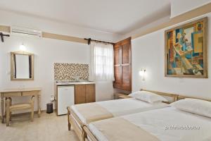 a hotel room with two beds and a desk at Philoxenia Studios 2 in Karpathos