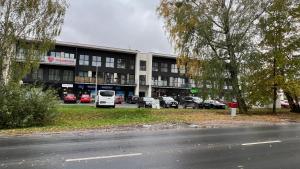un grand bâtiment avec des voitures garées dans un parking dans l'établissement Granatowy Apartament, à Grodzisk Mazowiecki