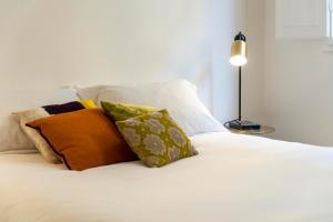 ein weißes Bett mit Kissen und einer Lampe in der Unterkunft Memory Atelier - apartment in Florence in Florenz