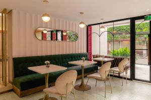 a restaurant with a green couch and tables and chairs at Hanoi Le Jardin Hotel & Spa in Hanoi