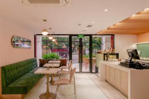 ハノイにあるHanoi Le Jardin Hotel & Spaの緑のソファ、テーブル、椅子が備わるレストラン