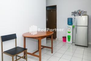 Una mesa y una silla en una cocina con nevera. en Ninja Room Pasteur Mitra RedDoorz, en Bandung