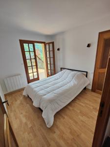 ein großes Bett in einem Schlafzimmer mit Holzboden in der Unterkunft CHALET BOUTX 6 PERSONNES in Boutx