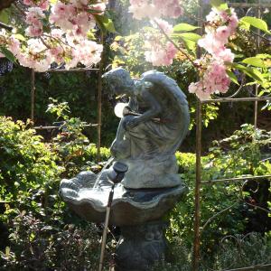 une statue d'une femme assise sur une fontaine dans un jardin dans l'établissement Bowral Road Art Gallery Bed and Breakfast, à Mittagong