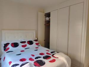 Un dormitorio con una cama blanca con flores rojas. en Casa Jaime, en Alcalá de Henares