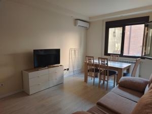 Una sala de estar con televisión y una mesa de comedor. en Apartamentos de Jaime, en Alcalá de Henares